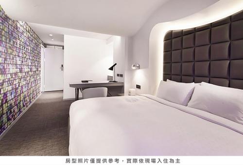 1 dormitorio con 1 cama blanca grande y escritorio en Royal Hotel Group- Central Park Branch, en Kaohsiung
