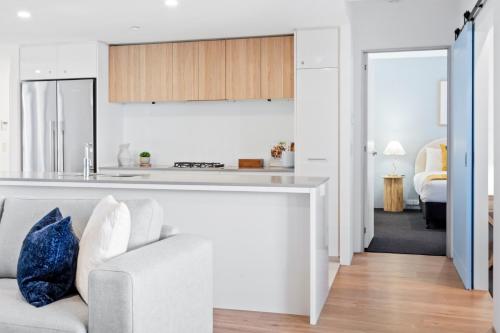 a white living room with a couch and a kitchen at Circle on Cavill - Gclr in Gold Coast