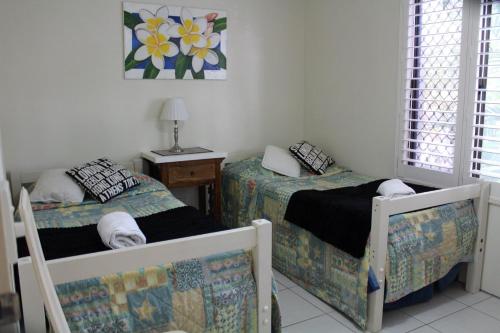 a bedroom with two beds and a table with a lamp at 1 Aarons Villa in Noosaville