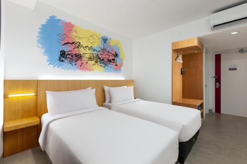 a bedroom with two beds and a painting on the wall at favehotel Kediri in Kediri