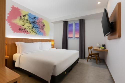 ein Hotelzimmer mit einem Bett und einem TV in der Unterkunft favehotel Kediri in Kediri