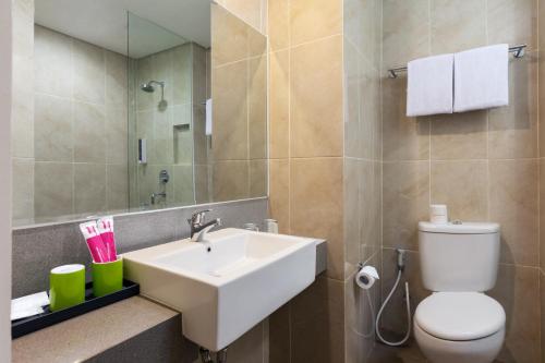 a bathroom with a sink and a toilet and a mirror at favehotel Kediri in Kediri