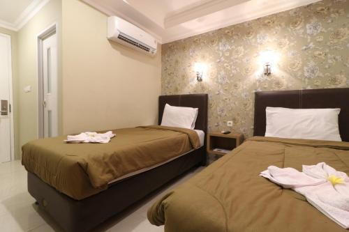 two beds in a hotel room with towels on them at Flamenco Urban Living in Jakarta