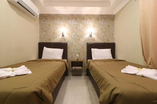 two beds in a hotel room with towels at Flamenco Urban Living in Jakarta