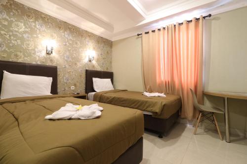 ein Hotelzimmer mit 2 Betten und Handtüchern darauf in der Unterkunft Flamenco Urban Living in Jakarta