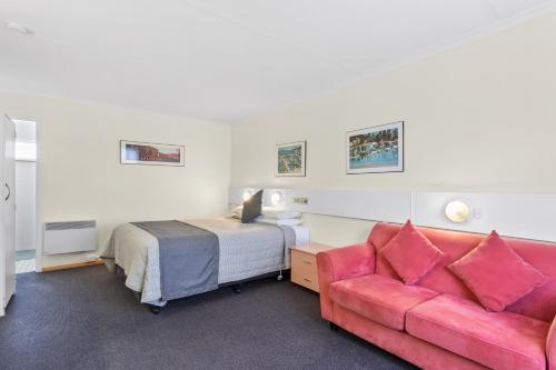 1 dormitorio con 1 cama y 1 sofá rosa en Martin Cash Motel en Hobart