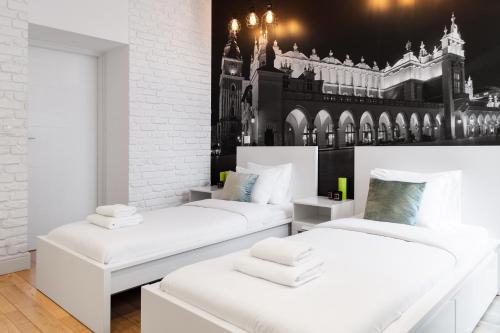 two white beds in a room with a building on the wall at Househost Apartment: Bonerowska 5/19 in Krakow