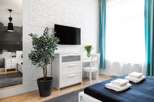 a living room with a tv on a white brick wall at Househost Apartment: Bonerowska 5/19 in Krakow