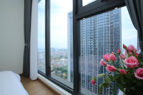 a vase of pink roses in a room with a window at Investland- Vinhomes Metropolis one, two, three, four bedrooms in Hanoi
