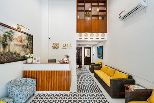 uma sala de estar com um sofá amarelo e cadeiras em LILA Hotel & Apartments em Cidade de Ho Chi Minh