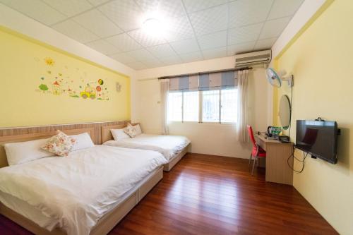 花蓮市的住宿－微加幸福民宿，一间设有两张床和一台电视的房间