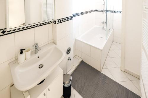W białej łazience znajduje się umywalka i lustro. w obiekcie Modern & Chic Apartment with Balcony w mieście Gravenbruch
