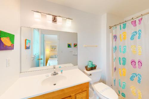 Un baño con lavabo, inodoro y espejo. en Pelican Paradise 770, en Avon