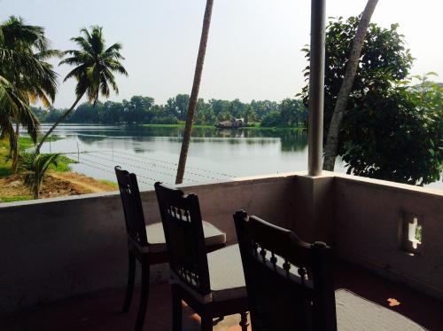 a table and chairs on a balcony with a view of a river at Ayana's Homestay in Alleppey