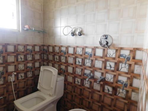 a bathroom with a toilet and a tiled wall at Cauvery Homestay in Somvārpet