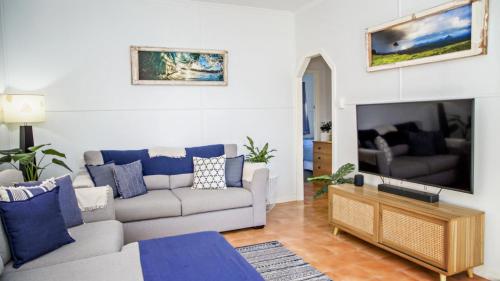a living room with a couch and a tv at Blue Beach House in Caloundra