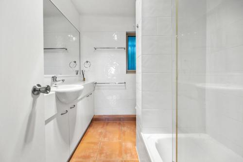a white bathroom with a sink and a shower at Peregian Beach Apartment in Peregian Beach