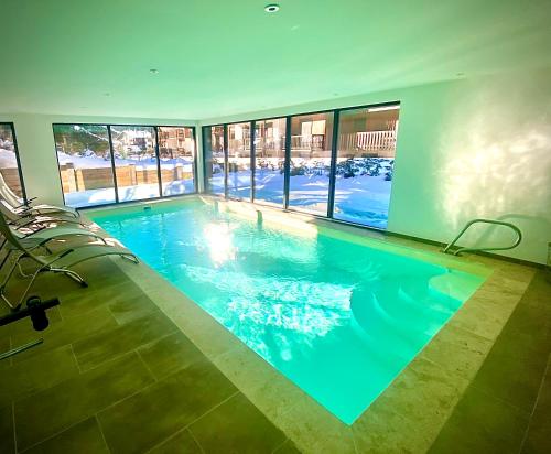 - une grande piscine d'eau bleue dans un bâtiment dans l'établissement Chalet Amour blanc, aux Houches