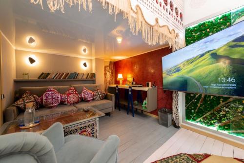 a living room with a large tv and a couch at Inn OZZ in Karagandy