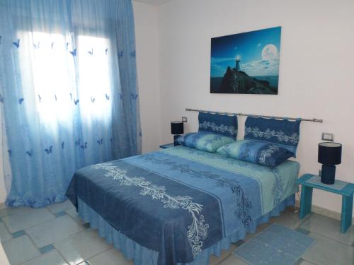 Un dormitorio con una cama azul y una ventana en The Blue Lighthouse, en SantʼAntìoco