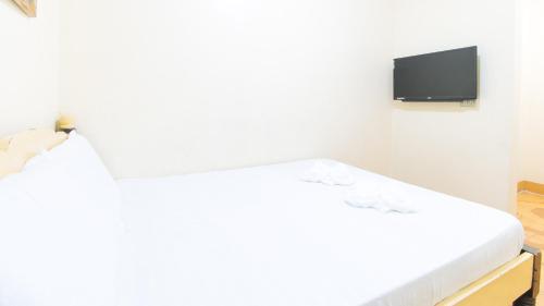 een witte kamer met een bed en een televisie bij Maliwalo Inn Tarlac by RedDoorz in Tarlac