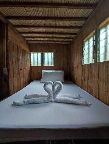 Virgin River Resort and Recreation Spot في Bolinao: سرير عليه منشفتين على شكل قلب