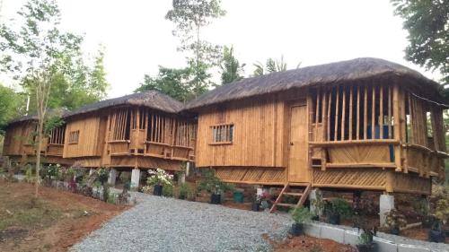 Virgin River Resort and Recreation Spot في Bolinao: كوخين خشبيين كبيرين مع اشجار في الخلف