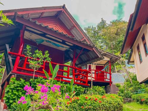 a red house with flowers in front of it at Tanouy Garden in Baan Khai