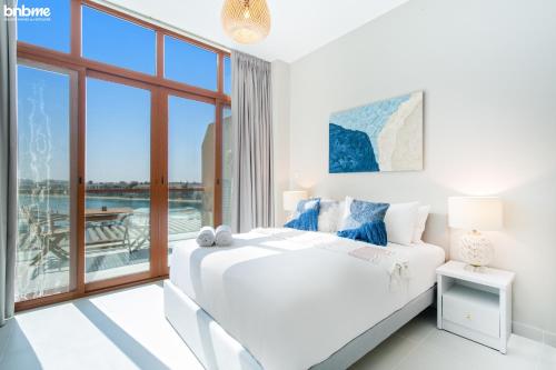Dormitorio blanco con cama y ventana grande en bnbmehomes - Studio in The Palm Near Nakheel Mall w Sea View - 205, en Dubái
