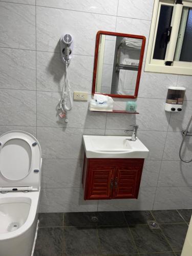 a bathroom with a toilet and a sink and a mirror at Downtown Accommodation in Jincheng