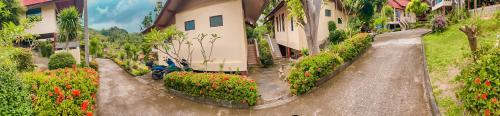 ein Bild eines Hauses mit Blumen im Hof in der Unterkunft Tanouy Garden in Baan Khai