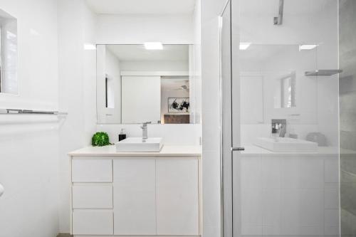 a white bathroom with two sinks and a shower at Coco Bella Retreat in Central Surfers - sleeps 6-8 in Gold Coast