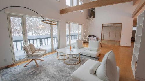a living room with white furniture and large windows at Annupuri Chalets - Niseko in Niseko