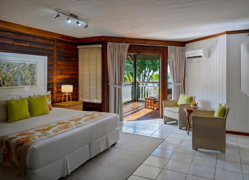 um quarto com uma cama e uma varanda em Acajou Beach Resort em Baie Sainte Anne