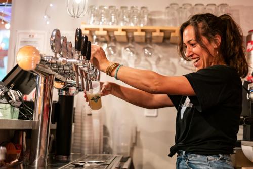 une femme fait un verre dans un bar dans l'établissement 1861 Châtel Hostel, à Châtel