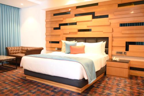 a bedroom with a large bed with a wooden wall at Ramada Plaza by Wyndham Jammu Vijaypur in Jammu