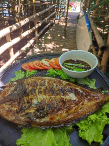 a fish on a plate with lettuce and tomatoes at Virgin River Resort and Recreation Spot in Bolinao