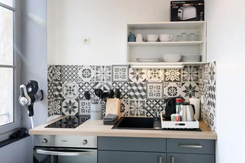 a kitchen with black and white tiles on the wall at N2 des Études Cosy Hypercentre Wifi ConciergerieDameCarcas in Carcassonne
