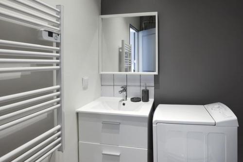 une salle de bain blanche avec un lavabo et un miroir dans l'établissement N2 des Études Cosy Hypercentre Wifi ConciergerieDameCarcas, à Carcassonne