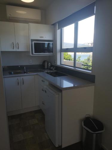 a kitchen with a sink and a microwave and a window at Paku Lodge Resort in Tairua