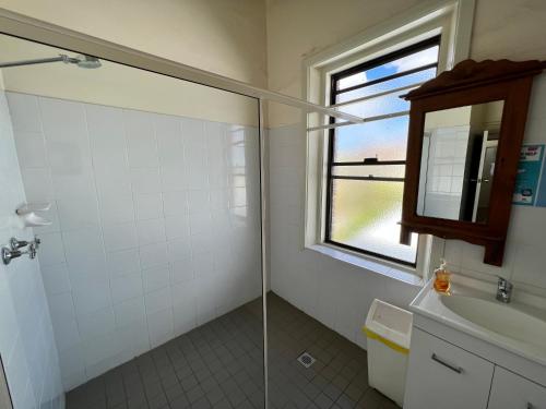 baño con ducha, lavabo y ventana en Black Lion Inn Hotel, en Broken Hill