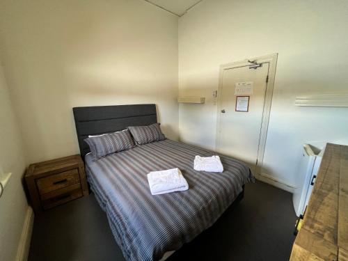 1 dormitorio con 1 cama con 2 toallas en Black Lion Inn Hotel, en Broken Hill