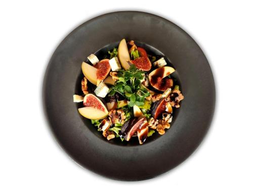 a black plate with a salad with fruit and nuts at Hotel Olympic Spa & Wellness in Ustroń