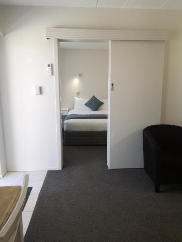 a bedroom with a bed and a door leading into a room at Paku Lodge Resort in Tairua