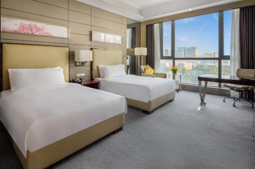 a hotel room with two beds and a desk at Crowne Plaza Shenzhen Longgang City Centre by IHG in Longgang