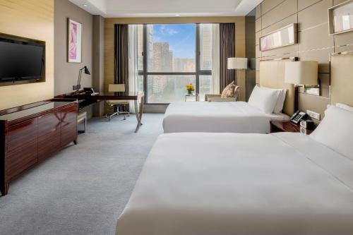 a hotel room with two beds and a desk and a television at Crowne Plaza Shenzhen Longgang City Centre by IHG in Longgang