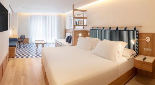 a bedroom with a large white bed and a living room at H10 Porto Poniente 4* Sup in Benidorm