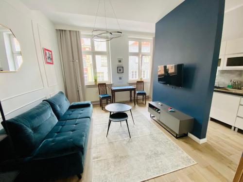 - un salon avec un canapé bleu et une table dans l'établissement Apartament KonDor Shekspir, à Gdańsk