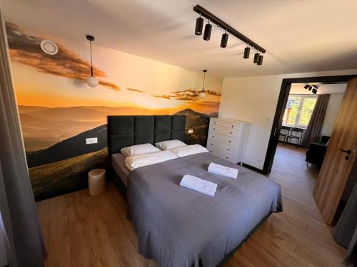a bedroom with a bed with a painting on the wall at Apartamenty Drewno i Kamień in Wetlina