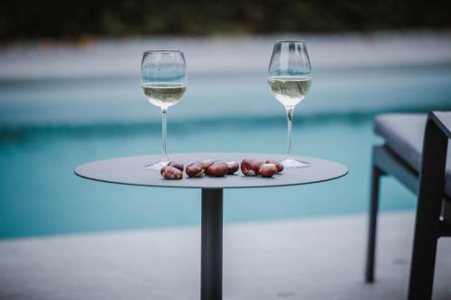 two glasses of wine on a table next to a pool at Vakantiehuis sINNE in Oostmalle